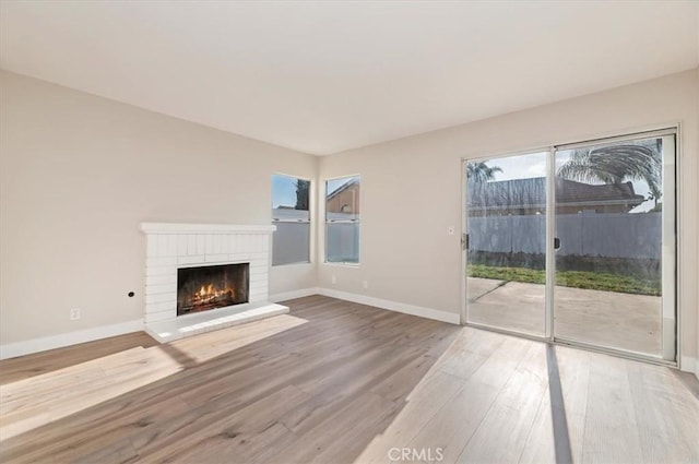 unfurnished living room featuring baseboards, a fireplace, and wood finished floors