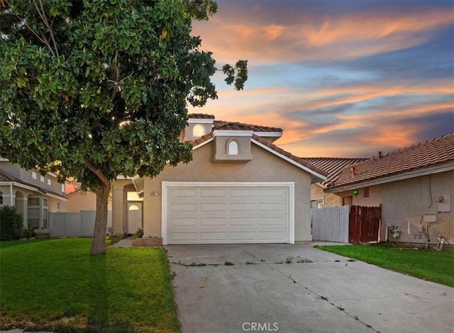 traditional home with concrete driveway, an attached garage, fence, and a yard