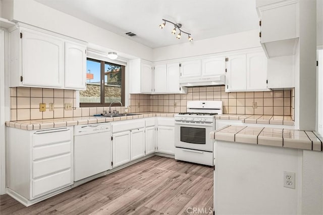 kitchen featuring white cabinets, under cabinet range hood, white appliances, and light wood-style flooring