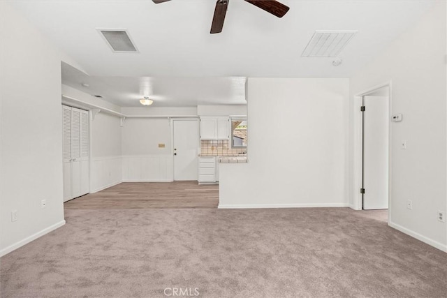 unfurnished living room with a ceiling fan, baseboards, light colored carpet, and visible vents