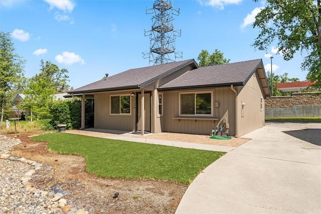 ranch-style house featuring fence, a front yard, roof with shingles, a patio area, and driveway