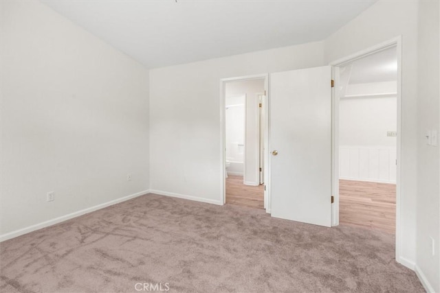 unfurnished bedroom featuring baseboards, carpet flooring, and a spacious closet