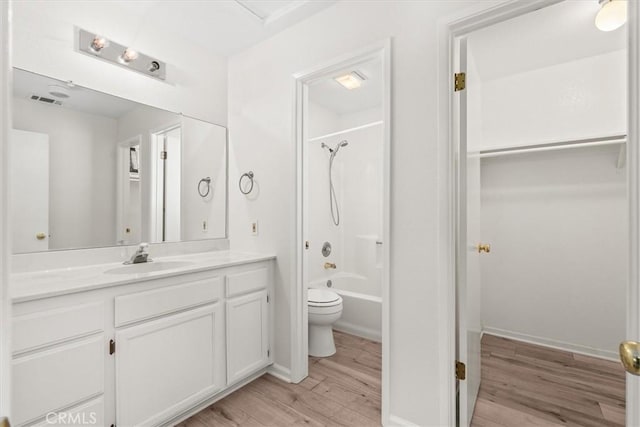 bathroom featuring visible vents, vanity, tub / shower combination, wood finished floors, and toilet