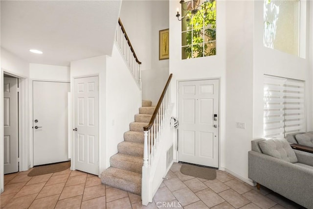 foyer featuring a high ceiling, light tile patterned floors, and stairway
