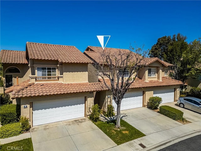 view of front facade with a tiled roof, an attached garage, concrete driveway, and stucco siding