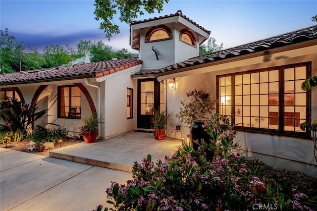 rear view of property with a tile roof and stucco siding