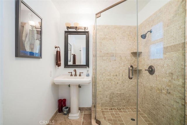 full bath featuring a sink, baseboards, and a shower stall