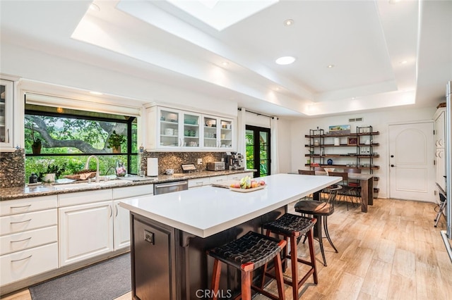 kitchen with a breakfast bar area, backsplash, a center island, white cabinets, and a tray ceiling