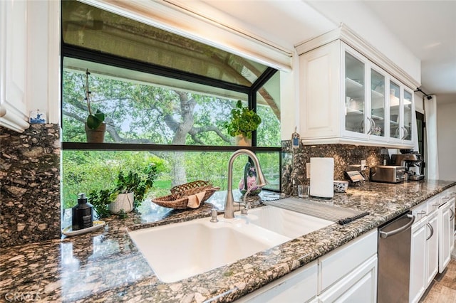 kitchen featuring a sink, glass insert cabinets, white cabinets, and tasteful backsplash