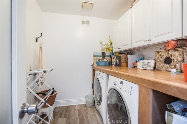 laundry room with visible vents, cabinet space, washing machine and dryer, and light wood-type flooring