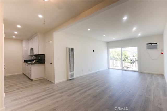 unfurnished living room with recessed lighting, a heating unit, a sink, and light wood-type flooring