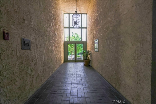 corridor with a healthy amount of sunlight, brick floor, and a towering ceiling