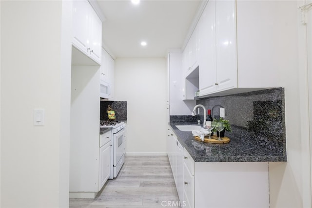 kitchen featuring white appliances, white cabinetry, tasteful backsplash, a sink, and light wood-style flooring