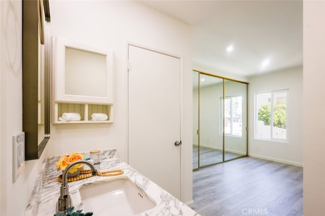 bathroom featuring recessed lighting, baseboards, a sink, and wood finished floors