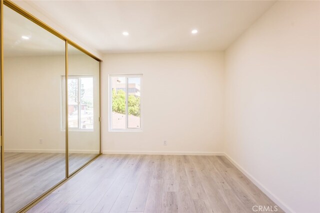 unfurnished bedroom with a closet, recessed lighting, light wood finished floors, and baseboards