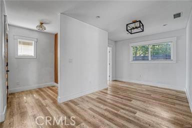 spare room with baseboards, wood finished floors, and visible vents