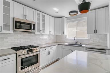 kitchen with a sink, appliances with stainless steel finishes, white cabinets, and tasteful backsplash