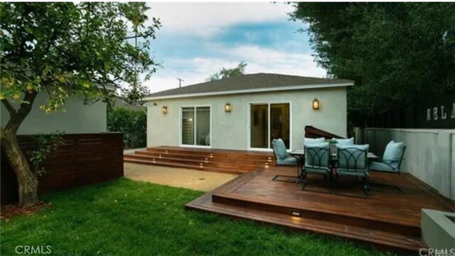 back of property featuring a deck, fence, outdoor dining area, and stucco siding