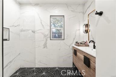 bathroom featuring vanity and a marble finish shower