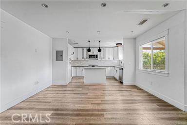 kitchen featuring light wood-style floors, a center island, baseboards, and appliances with stainless steel finishes