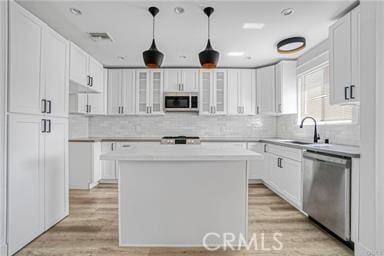 kitchen featuring decorative backsplash, glass insert cabinets, white cabinets, and stainless steel appliances