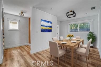 dining room featuring baseboards, light wood-type flooring, and visible vents