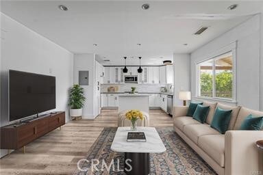 living room featuring light wood-style floors, electric panel, and visible vents