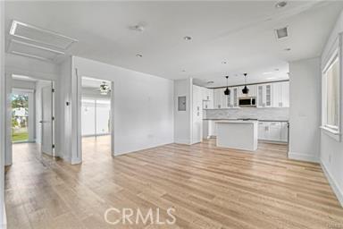 unfurnished living room with light wood-style floors and attic access