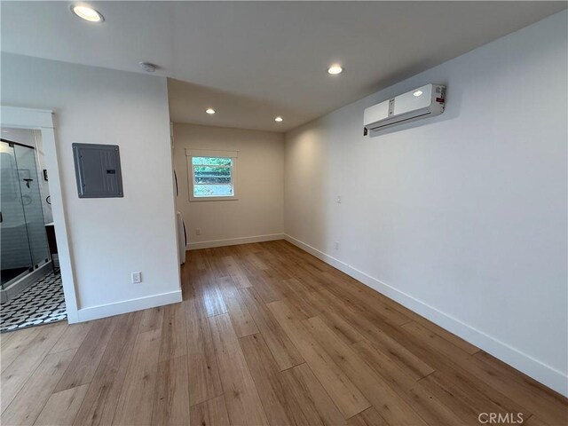 interior space featuring baseboards, a wall unit AC, wood finished floors, and electric panel