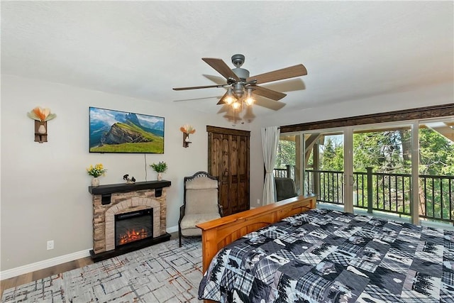 28844 Cedar Dr, Lake Arrowhead, CA 92352 - bedroom featuring access to exterior, a stone fireplace, a ceiling fan, and wood finished floors