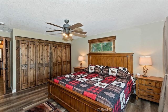 bedroom with a ceiling fan, dark wood-style floors, and a textured ceiling