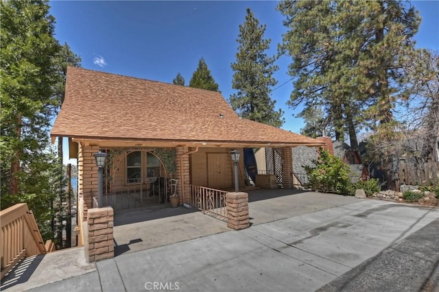 view of front of house featuring roof with shingles, covered porch, and concrete driveway