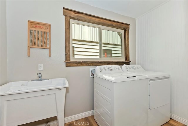 washroom with laundry area, light wood-style floors, baseboards, a sink, and independent washer and dryer