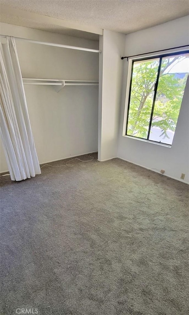 unfurnished bedroom with carpet floors, a closet, and a textured ceiling