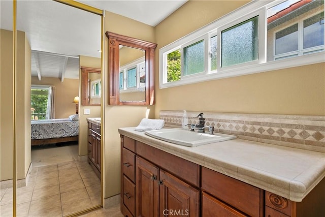 ensuite bathroom with vanity, tile patterned floors, ensuite bath, and beam ceiling