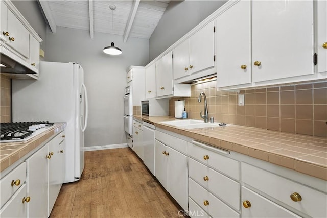 kitchen with a sink, decorative backsplash, tile countertops, and white appliances