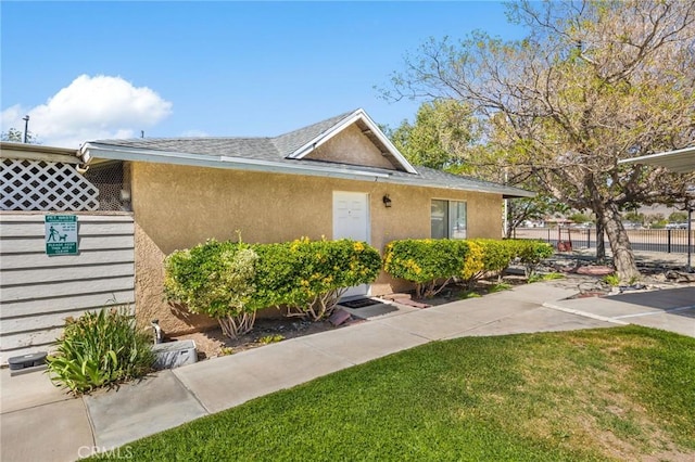 exterior space with stucco siding, a lawn, and fence