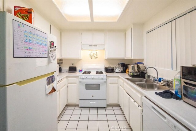 kitchen with white appliances, light countertops, under cabinet range hood, white cabinets, and a sink