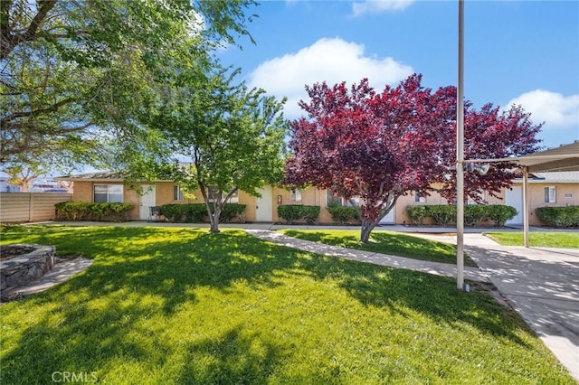 view of front facade featuring fence, stucco siding, and a front lawn