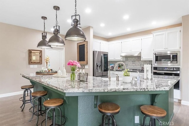 3065 Tierra Mesa, Atascadero, CA 93422 - kitchen with appliances with stainless steel finishes, under cabinet range hood, white cabinets, a breakfast bar area, and recessed lighting