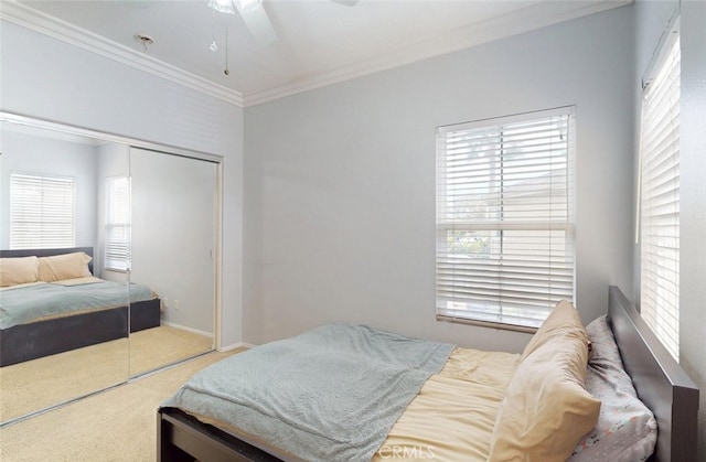 carpeted bedroom featuring a closet, ornamental molding, baseboards, and a ceiling fan