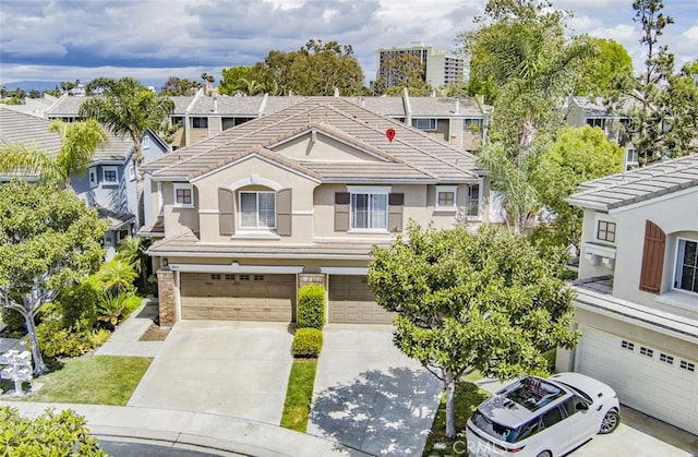 view of front facade featuring an attached garage, driveway, a tile roof, and stucco siding