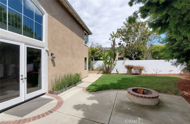 view of yard featuring a patio, a fire pit, fence, and french doors