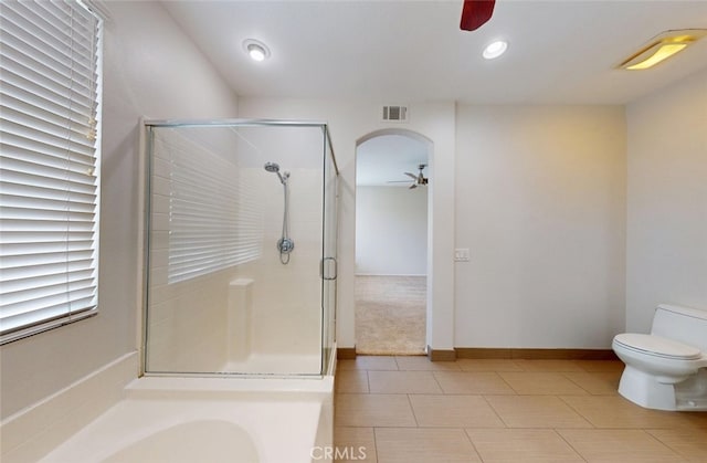 bathroom with visible vents, ceiling fan, a stall shower, and toilet