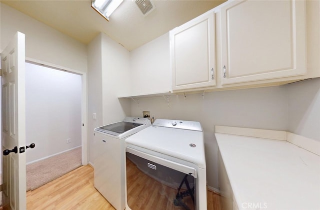 laundry area featuring visible vents, cabinet space, baseboards, light wood-style floors, and washer and clothes dryer