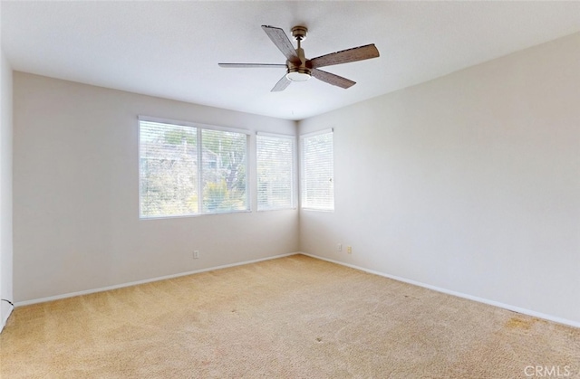 carpeted empty room with a ceiling fan and baseboards