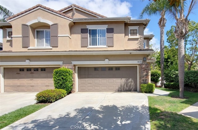 townhome / multi-family property featuring an attached garage, concrete driveway, a tile roof, and stucco siding