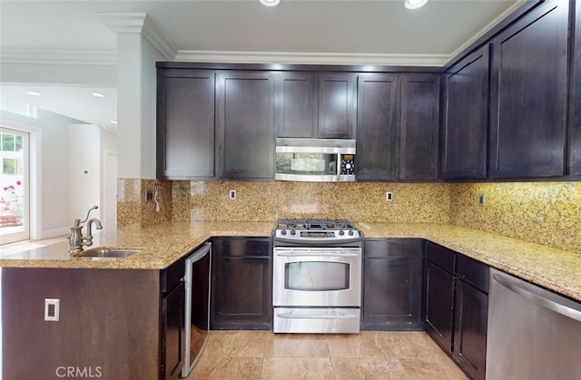 kitchen featuring crown molding, a peninsula, light stone countertops, a sink, and appliances with stainless steel finishes