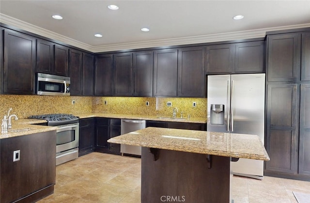kitchen featuring dark brown cabinetry, crown molding, light stone countertops, a sink, and stainless steel appliances