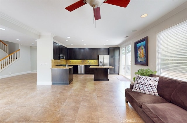 interior space with decorative backsplash, ornamental molding, a kitchen island, open floor plan, and appliances with stainless steel finishes